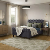 Neatly arranged bedroom with a purple bed, green pillows, and wooden furniture.