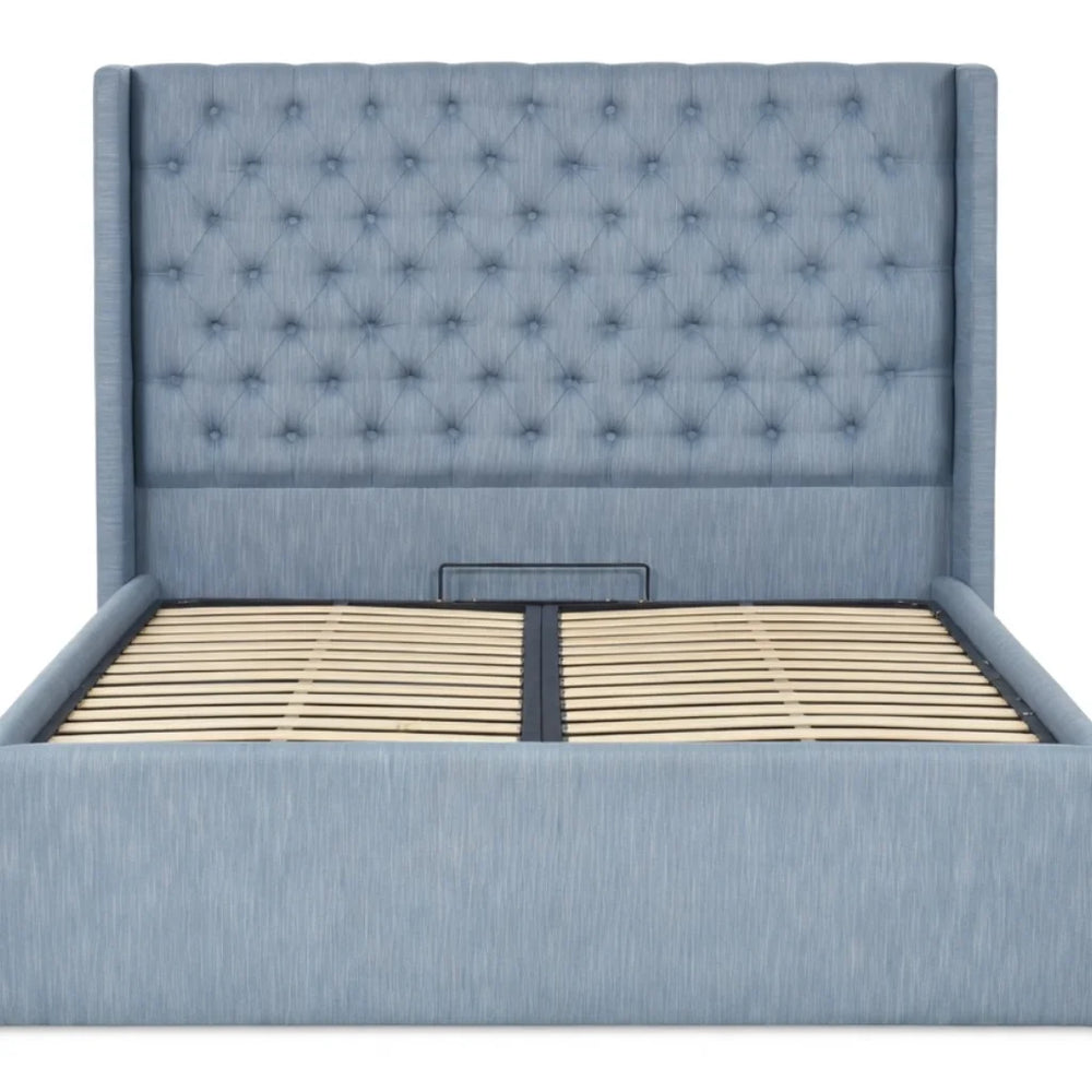 Side angle view of the light blue tufted storage bed with gas lift mechanism open, showcasing the storage space and headboard